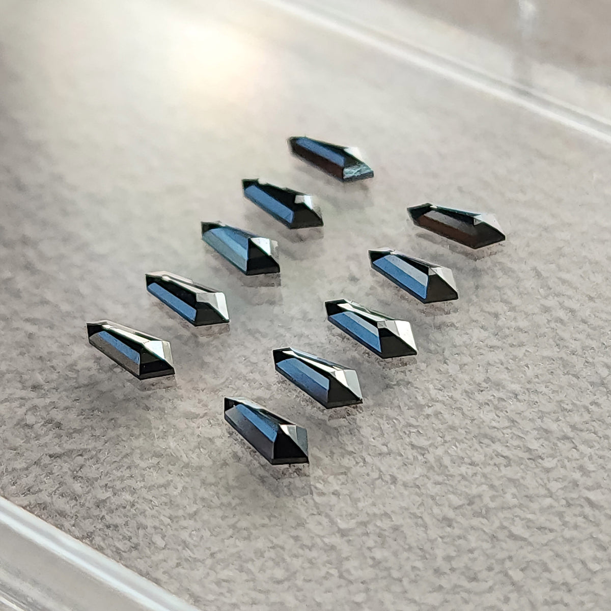Angled black shield-diamond group on gray paper, showing depth and blue-gray highlights on reflective facets.