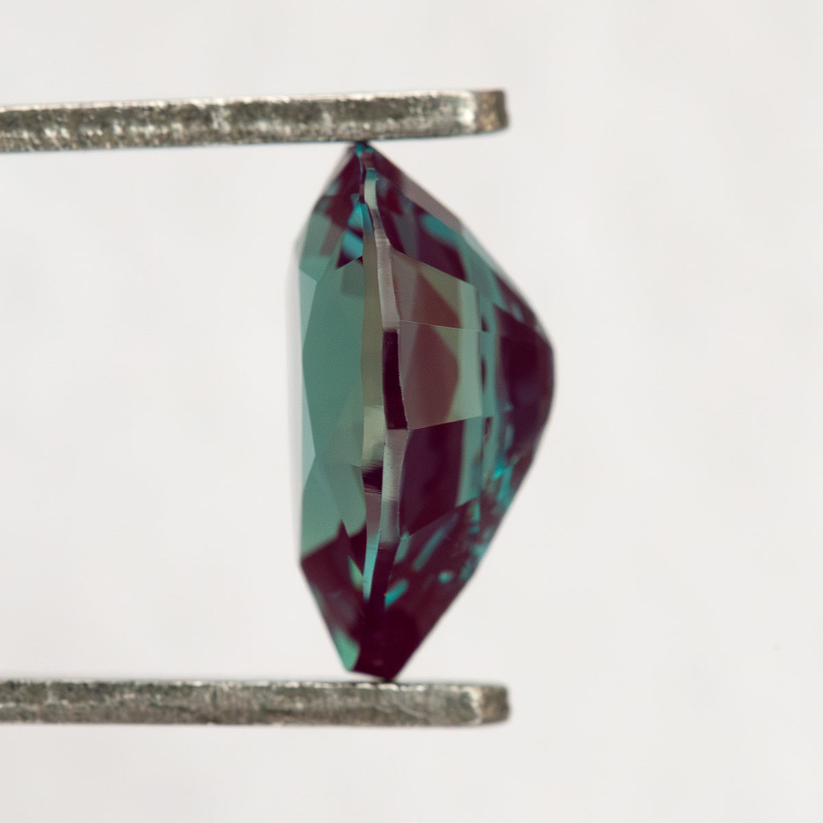 Side profile of the pear sample in tweezers, showing its crown and pavilion depth.