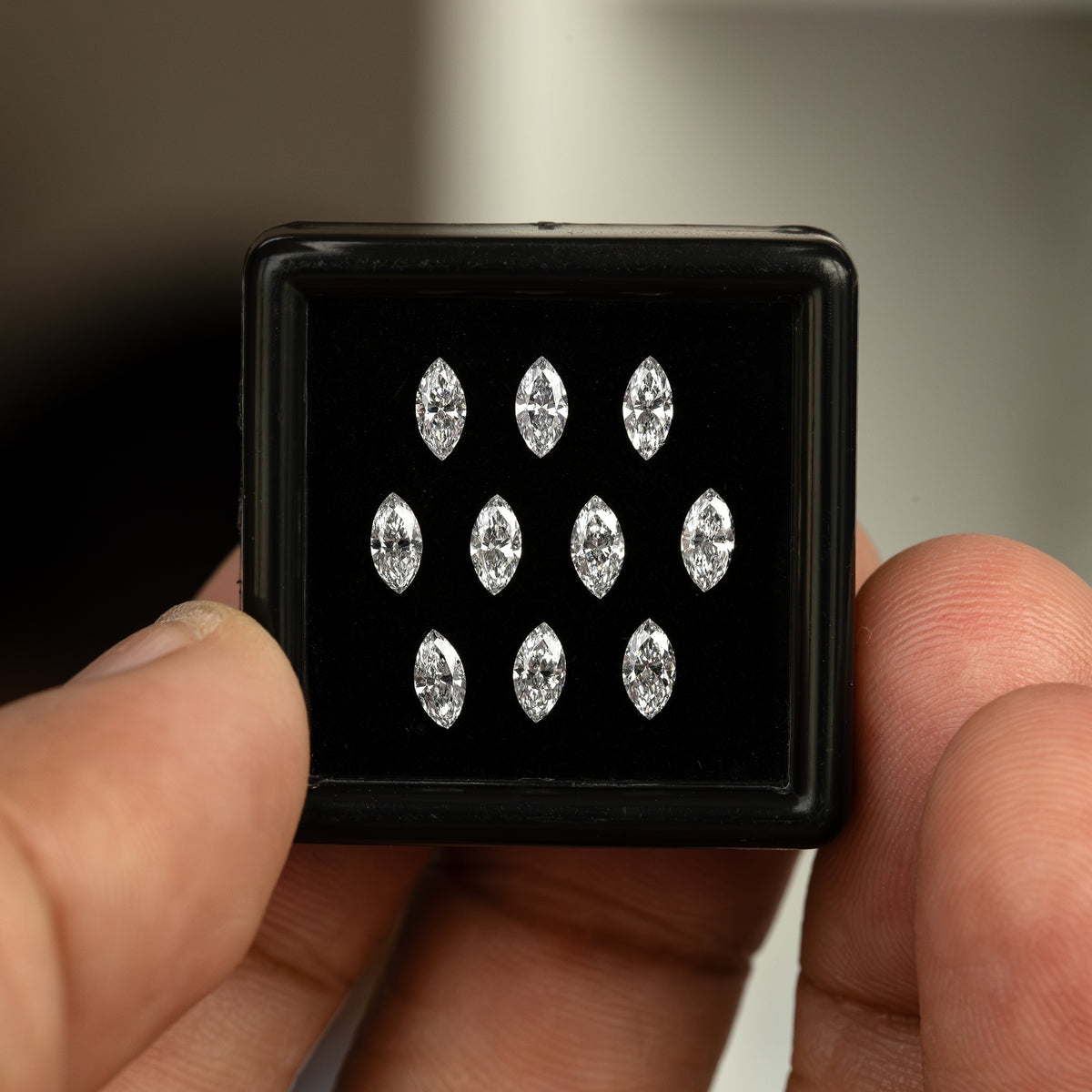 Ten marquise diamonds in a black display box held between fingers; parcel reference, not the quantity included in a single-piece purchase.