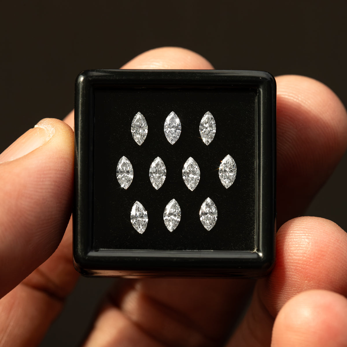 Close handheld black box containing ten marquise diamonds, showing the calibrated parcel rather than a sale pack.