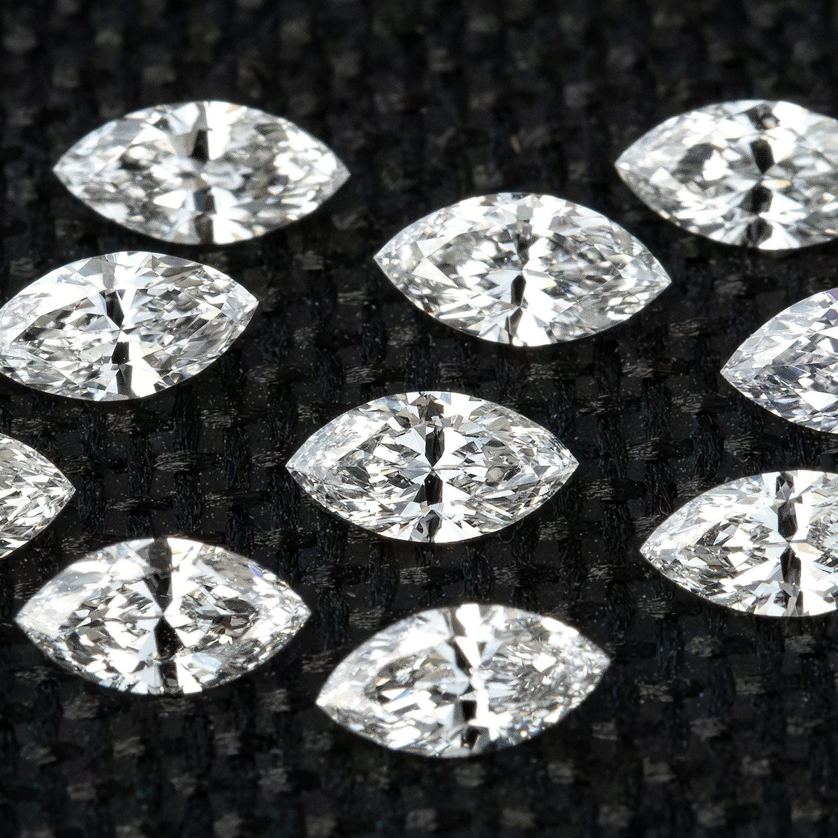 Group of calibrated 4 x 2 mm natural marquise diamonds on black fabric.