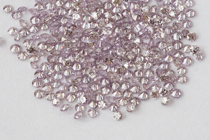 Close view of representative 1mm natural purple-pink round diamond stock on a white background.