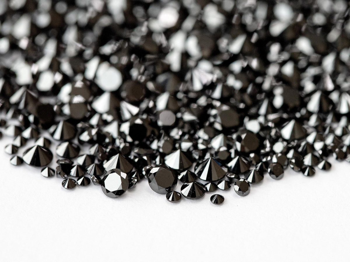 Close macro of representative black diamond melee showing round brilliant crowns and dark reflections.