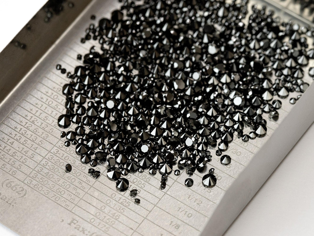 Color-enhanced natural black round diamond melee on a sorting tray; gallery is not a size chart.