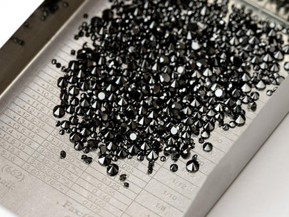 Color-enhanced natural black round diamond melee on a sorting tray; gallery is not a size chart.