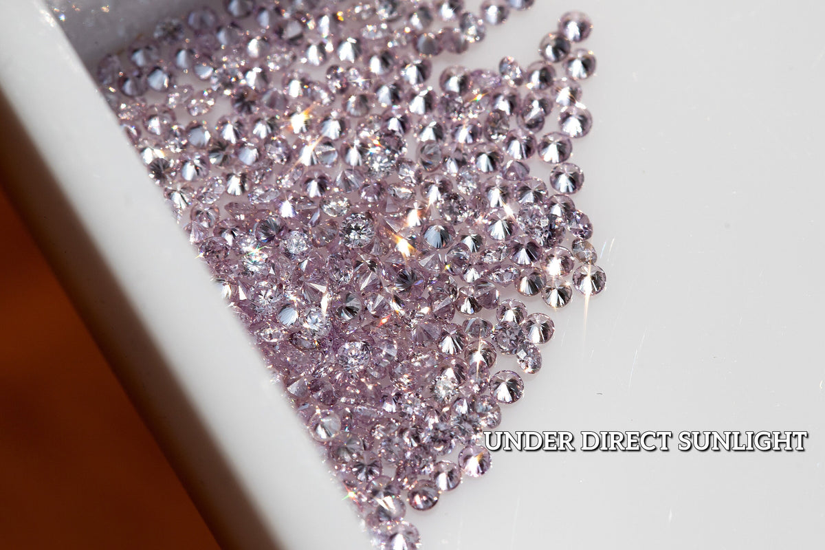 Representative purple-pink round diamond melee in a sorting tray under daylight.
