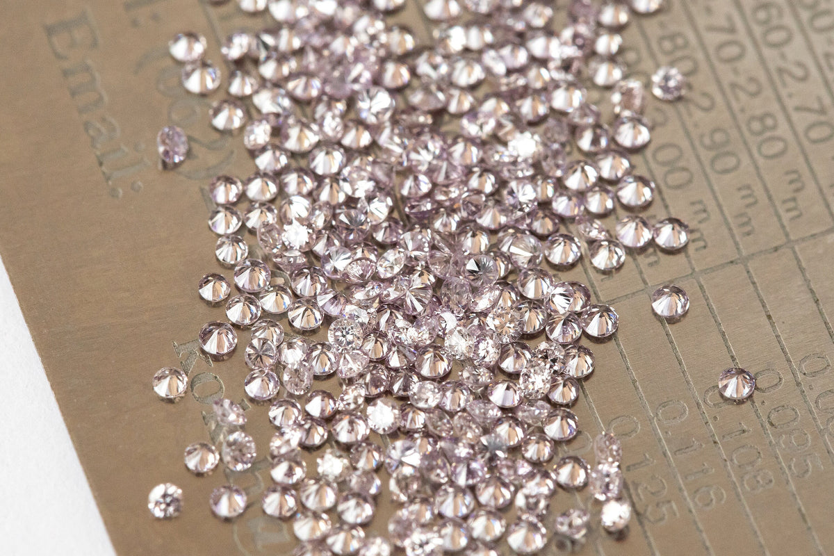Representative 1mm purple-pink diamond melee on a measurement grid for scale; five stones per order.