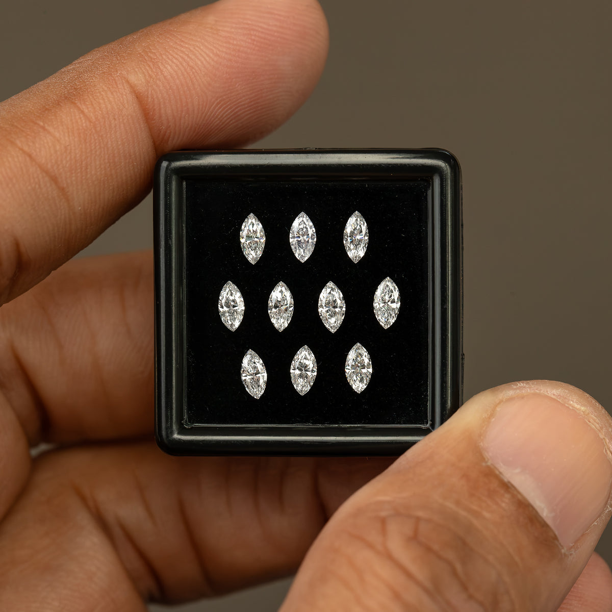 Ten-diamond marquise display box held upright between a thumb and finger for a scale comparison.