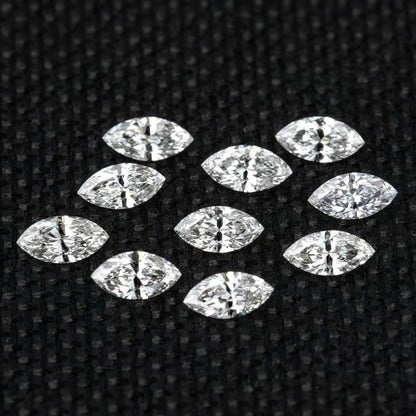 Ten loose marquise diamonds spread face-up on black woven fabric as a calibrated-supply reference.