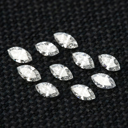 Angled layout of ten loose marquise diamonds on black fabric, with different tilts showing facet reflections.