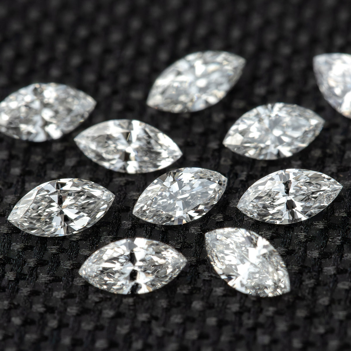 Loose marquise-diamond group on dark fabric, with brighter foreground stones and softer background focus.