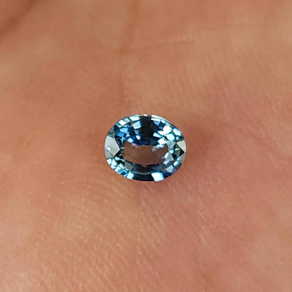 Alternate palm view of the oval sapphire, showing blue, gray and dark facet reflections.