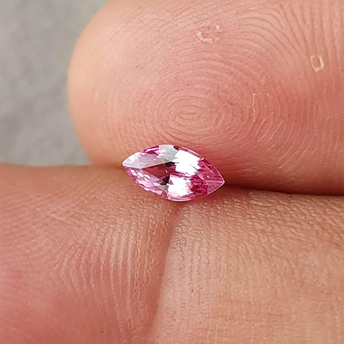 Alternate fingertip view of the pink marquise sapphire with stronger white reflections across the center.