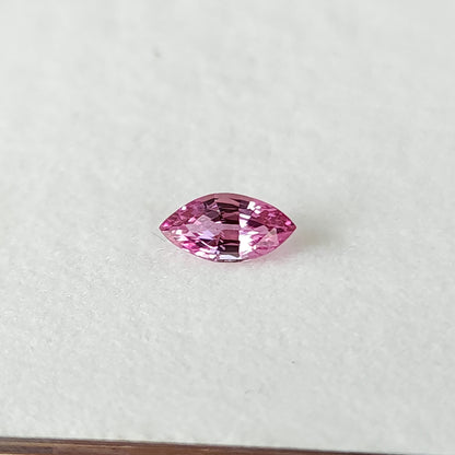 Wider white-pad view of the marquise sapphire, with dark and bright reflections across its center.