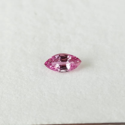 Close alternate face-up view of the pink marquise sapphire on a white pad.