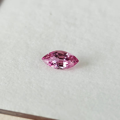 The marquise sapphire at a shallow angle on a white pad, with a tray edge visible along the bottom.