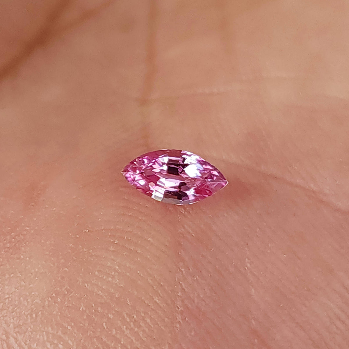 Alternate palm view of the marquise sapphire with bright reflections on the upper facets.