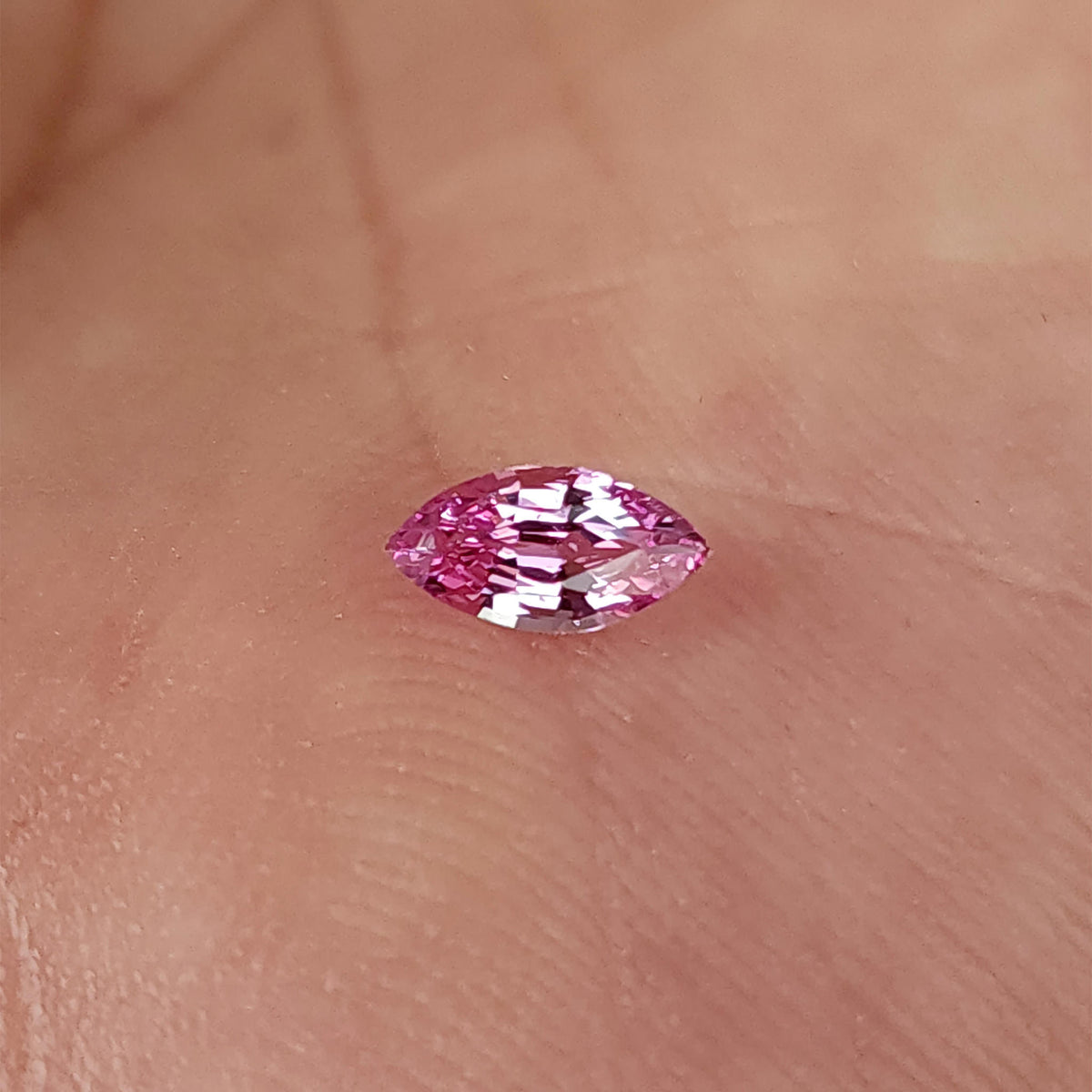 Wider palm view of the pink marquise sapphire and surrounding skin.