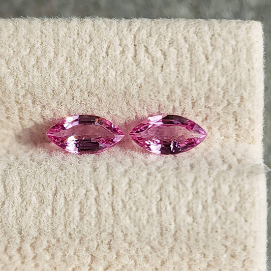 The complete pink marquise sapphire pair shown side by side face-up on a cream display pad.