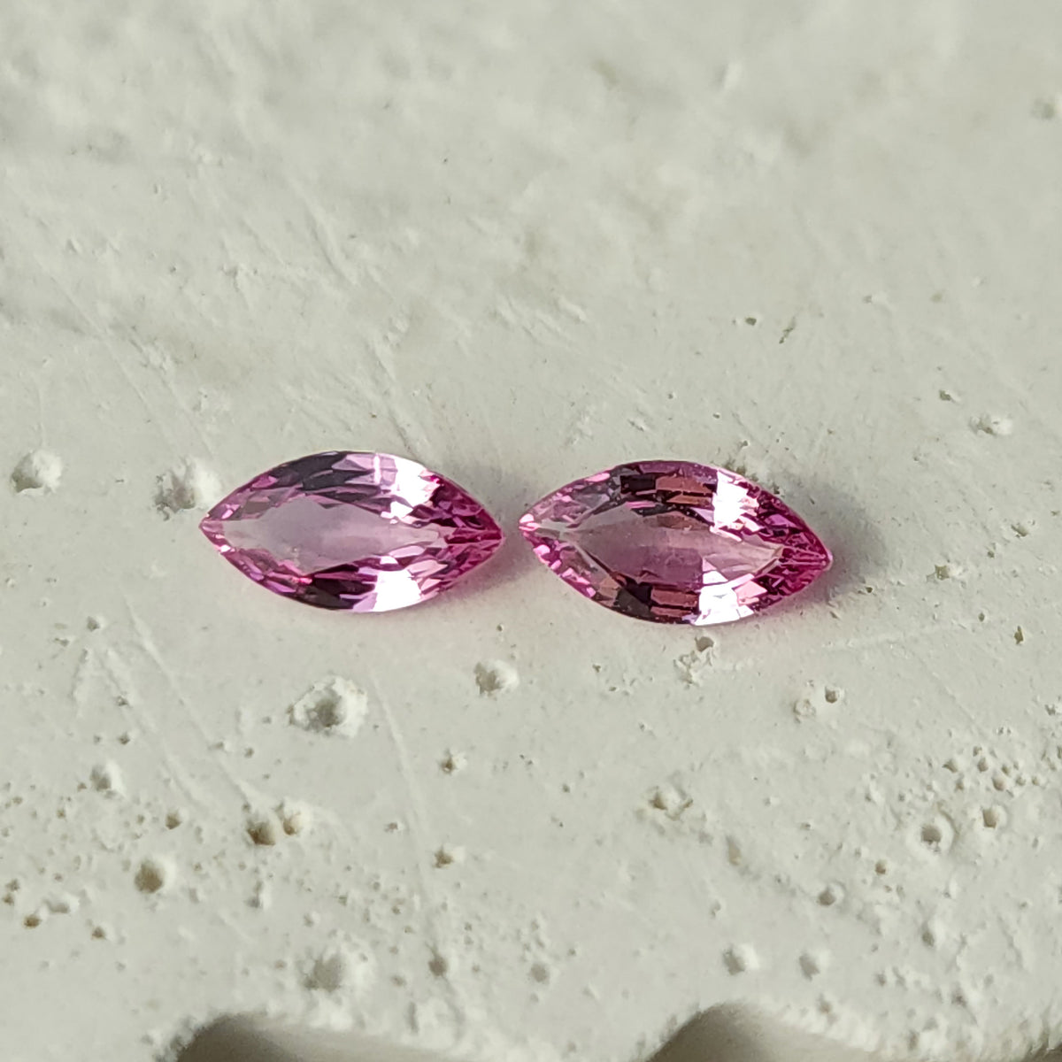 Alternate face-up view of the sapphire pair on a textured white surface, with both full outlines visible.