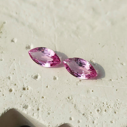 Closer tilted view of the sapphire pair on a textured white surface, showing different facet reflections.