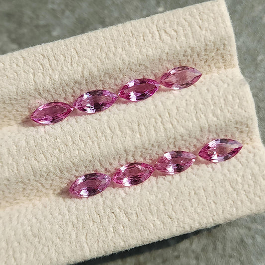 Close face-up view of the complete eight-sapphire parcel in two rows of four on a cream display pad.
