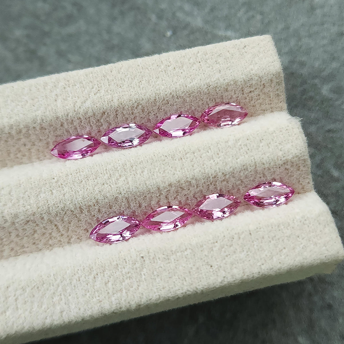 Low angled view of the eight marquise sapphires, with pale reflections on their central facets.