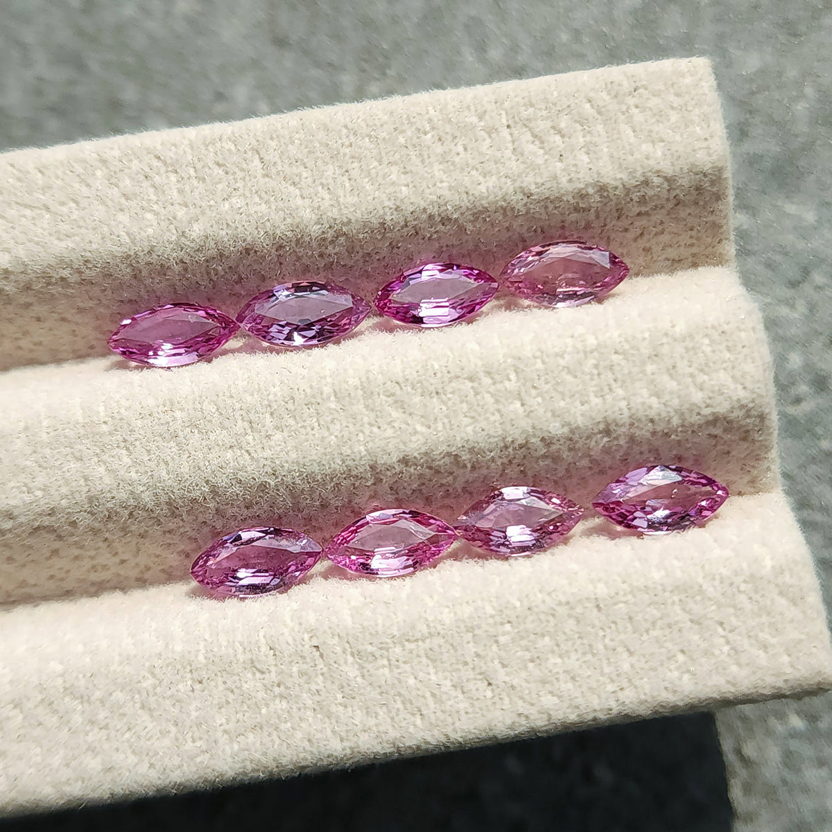 Eight marquise sapphires viewed from a shallow angle across two grooves in the display pad.