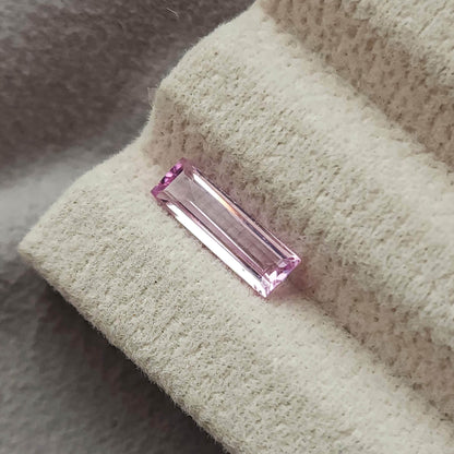 The baguette sapphire viewed diagonally on a cream pad, showing long parallel reflections.