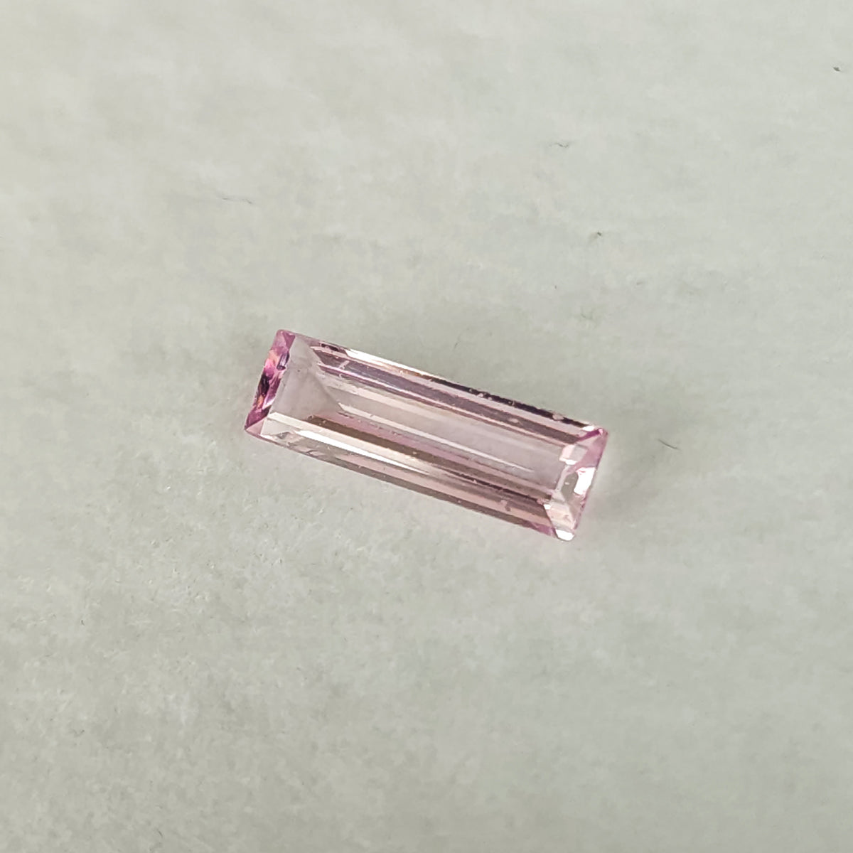 Alternate white-pad view of the baguette sapphire at a shallow diagonal angle.