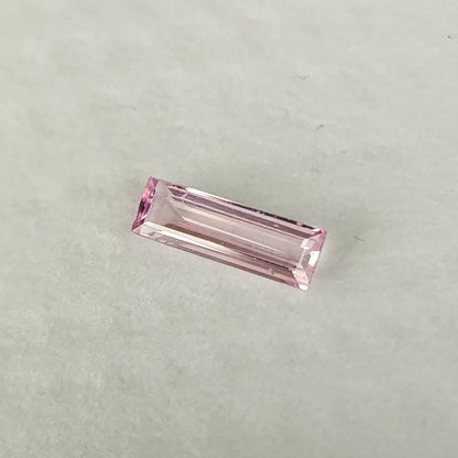 Alternate white-pad view of the baguette sapphire at a shallow diagonal angle.