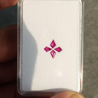Four pink kite rubies arranged in a cross on a white tray, shown with the complete tray and hand.