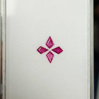 Four pink kite rubies seen face-up on a white tray with its clear right edge visible.