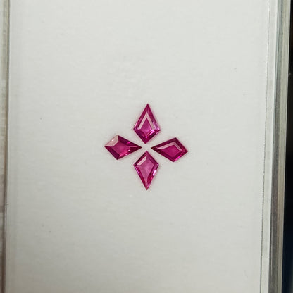 Wider face-up view of the complete four-kite ruby set near the lower portion of the white tray.