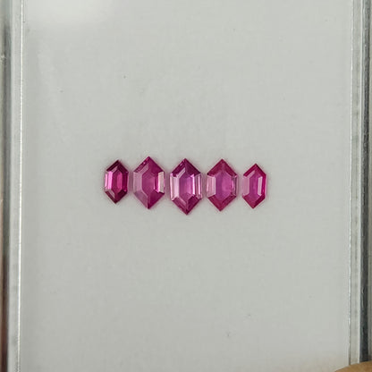 The five pink rubies tilted in a row, with brighter reflections on their facets.