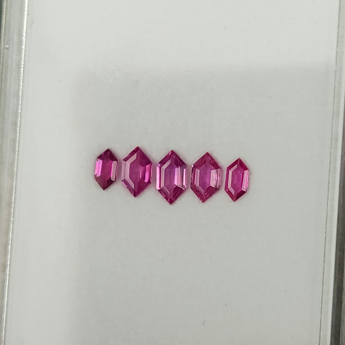 Another angled view of the five geometric rubies on the white tray.