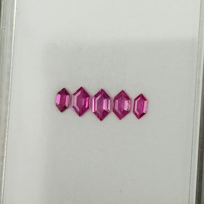 Another angled view of the five geometric rubies on the white tray.