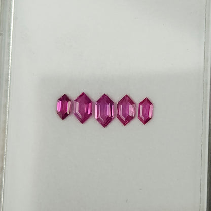 Five pink rubies viewed from an oblique angle, with their elongated outlines visible.