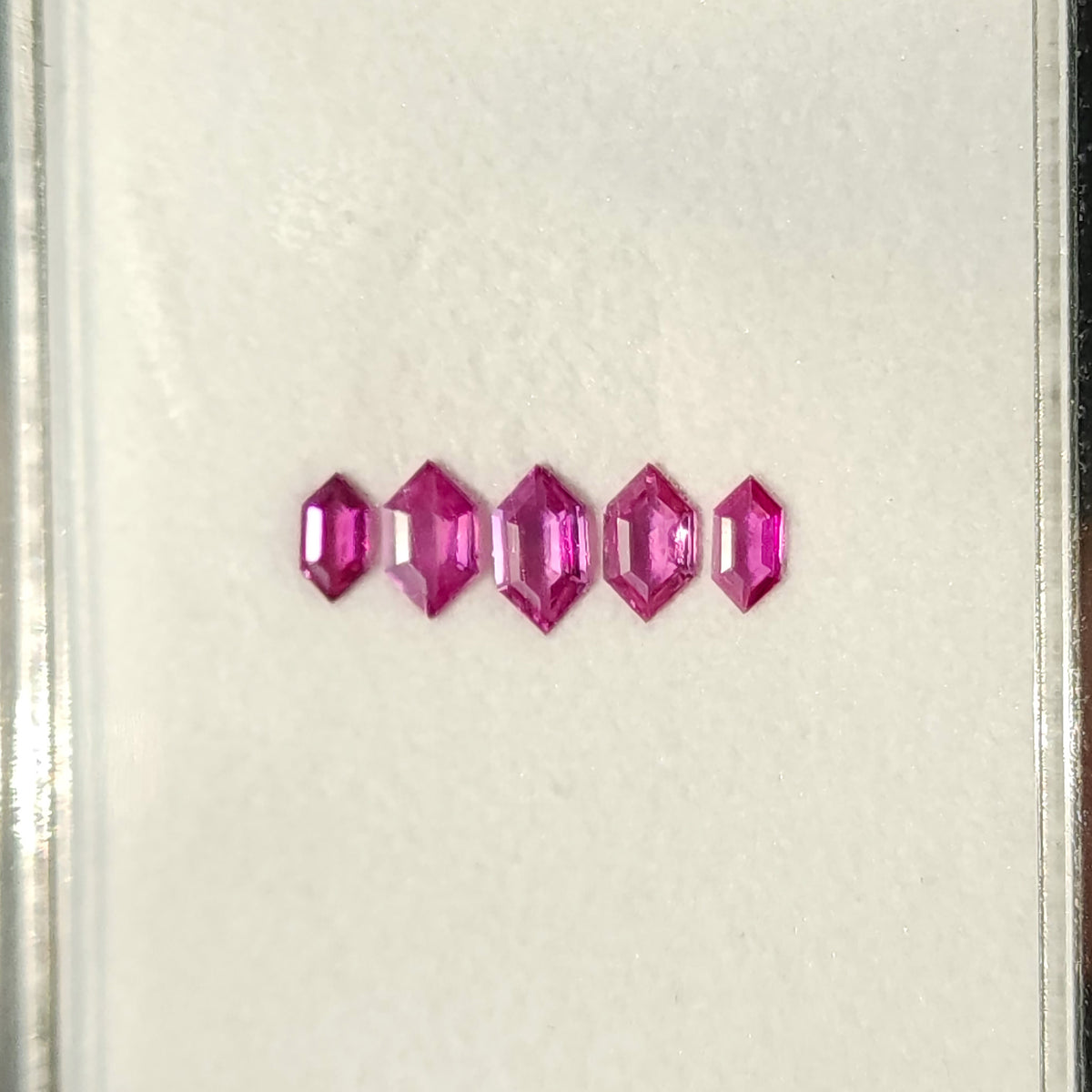 Complete five-ruby row on a white tray with bright highlights.