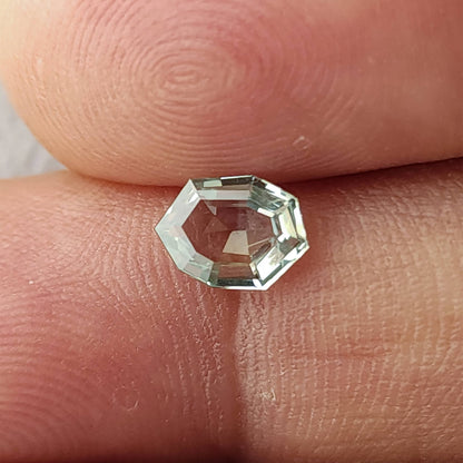 Mint green octagonal sapphire between two fingertips for scale, viewed face-up.