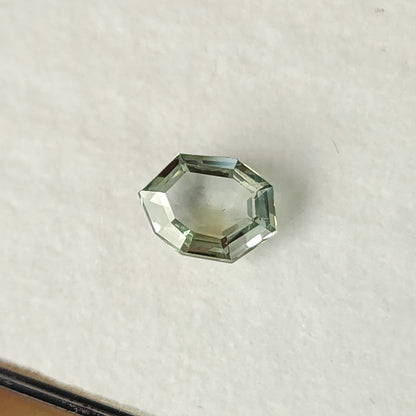 Mint green sapphire face-up on a white pad, showing its eight-sided outline and step facets.