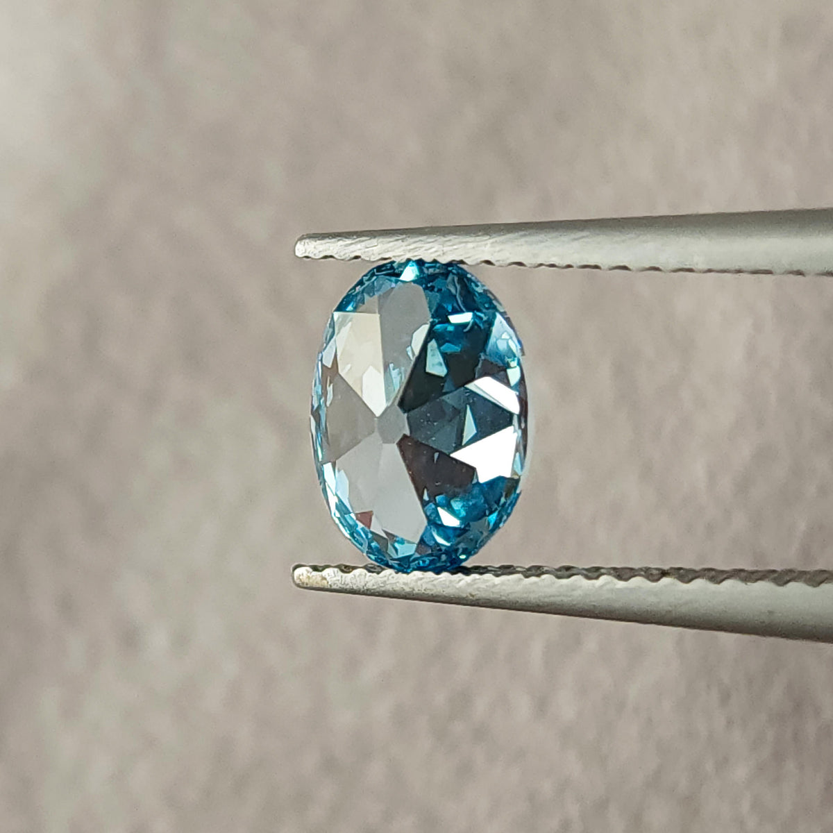 Alternate rotated tweezers view of the oval diamond with pale reflections.