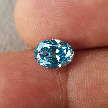 Blue oval diamond viewed slightly farther away between fingertips.
