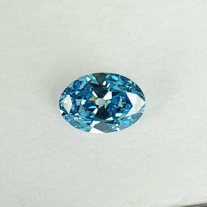 Close face-up view of the blue oval diamond on a white pad.