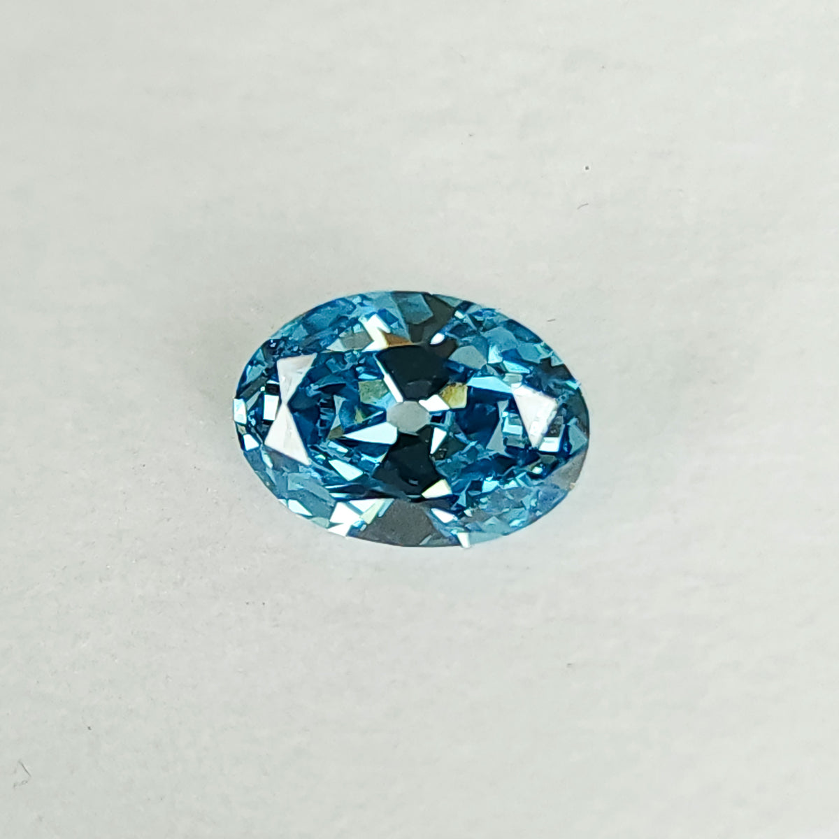 Blue oval diamond on a white pad at a slightly tilted angle.