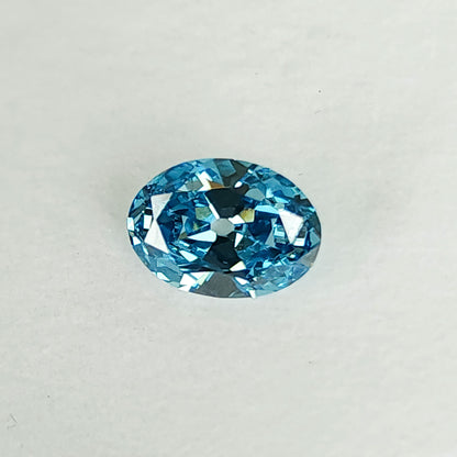 Blue oval diamond on a white pad at a slightly tilted angle.