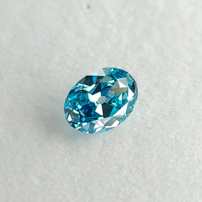 Blue oval diamond tilted on a pale surface, showing broad reflective facets.