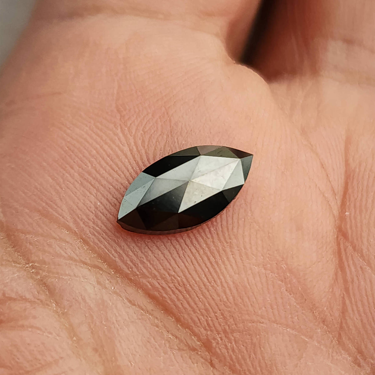 Alternate palm view of the black marquise diamond, showing its elongated outline and dark perimeter.