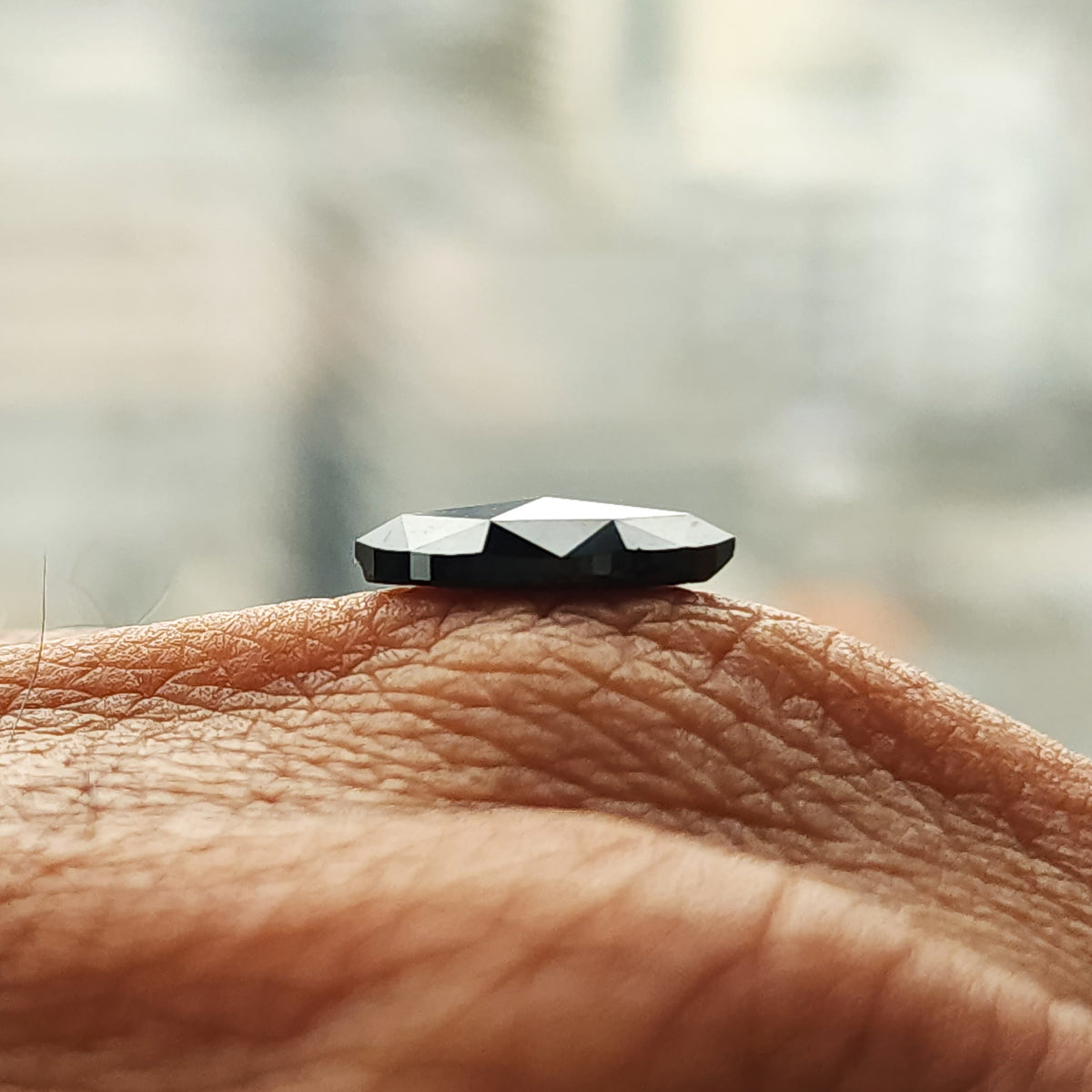 Low side-profile view of the black marquise diamond on a hand, showing the raised faceted crown.