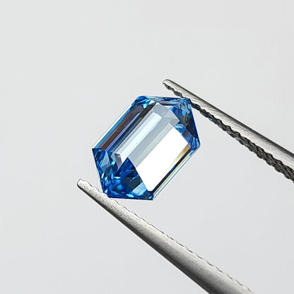 Blue hexagonal diamond tilted in tweezers, showing broad pale reflections inside the outline.